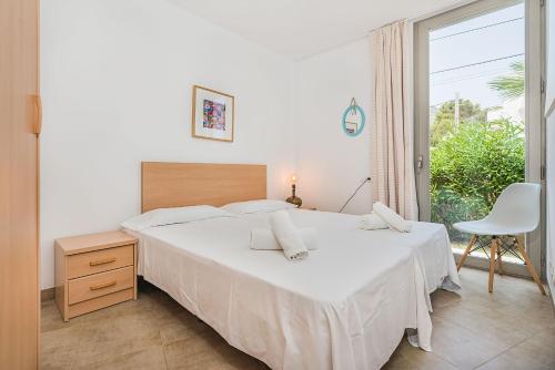 een slaapkamer met een groot wit bed en een raam bij Molins 6 in Cala de Sant Vicent