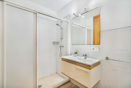 een witte badkamer met een wastafel en een douche bij Molins 6 in Cala de Sant Vicent