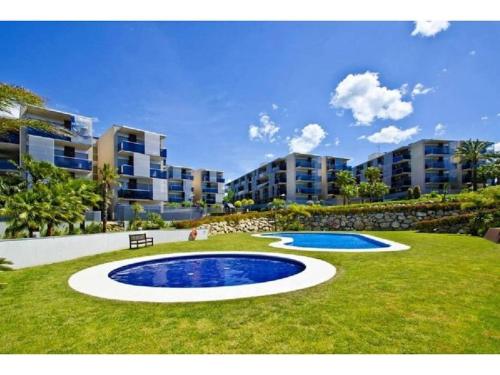 a pool in the middle of a lawn with buildings at Magnifico Paradis Village in Salou