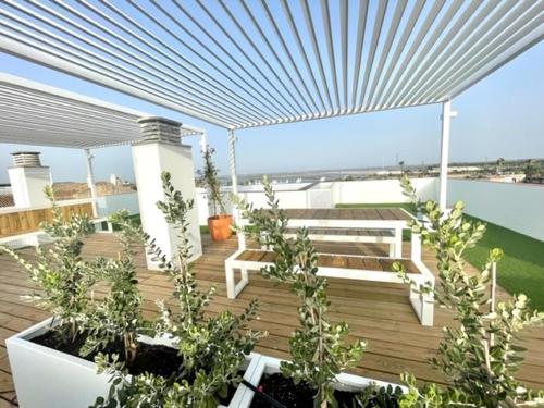 um deque de madeira com plantas e uma pérgola em GATU PREMIUM Las Caracolas, Aire C, parking y wifi em El Puerto de Santa María