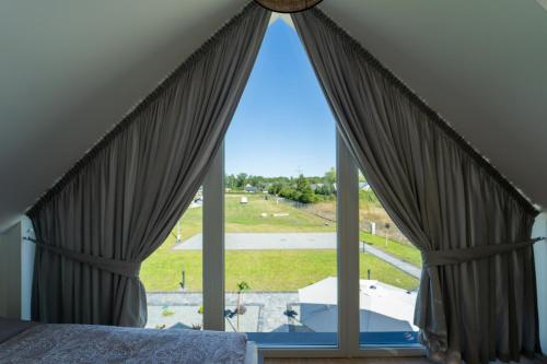 a bedroom with a large window with a view of a field at Bałtyckie Zacisze Kopalino in Kopalino