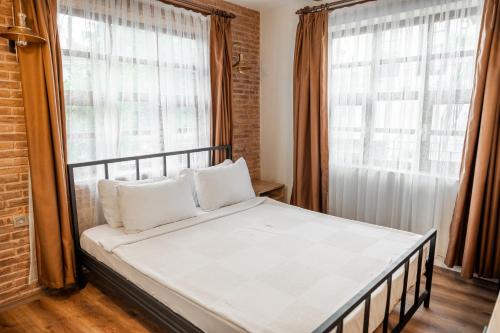 Bett mit weißen Kissen in einem Zimmer mit Fenstern in der Unterkunft Blue Sea Garden in Antalya