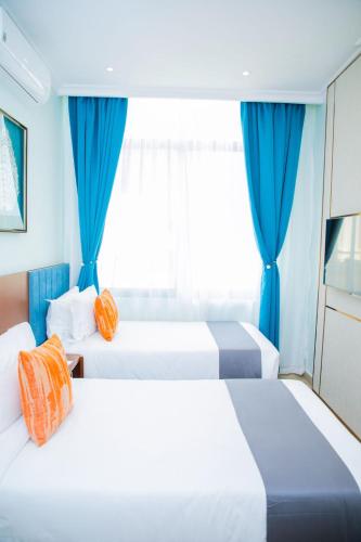 two beds in a hotel room with blue curtains at Best Western Dodoma City Hotel in Dodoma