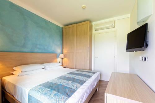 a bedroom with a large bed and a flat screen tv at Lake Garda Resort in Moniga
