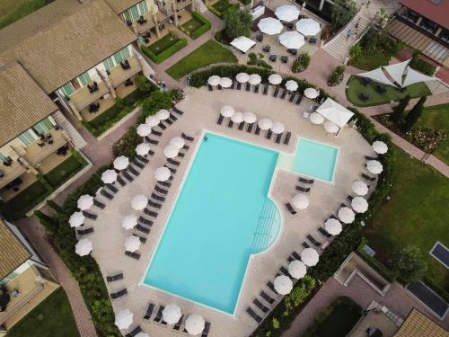 een uitzicht over een zwembad met tafels en stoelen bij Lake Garda Resort in Moniga