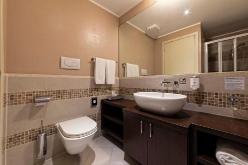 a bathroom with a white toilet and a sink at Lake Garda Resort in Moniga