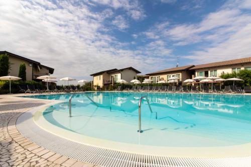 a large swimming pool with chairs and umbrellas at Lake Garda Resort in Moniga