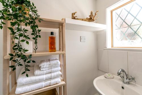 Un baño con lavabo y estante con toallas. en The Annex - Unparalleled Beach Front Luxury Accommodation - Private South West Facing Patio Area - Pet Friendly - Sky - Netflix - Super Fast WI-FI - Stones Throw To The Beach, en Southbourne