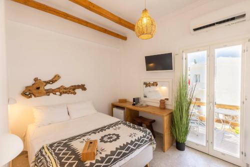 a bedroom with a bed and a desk and a window at Parosquare Central Suites in Parikia