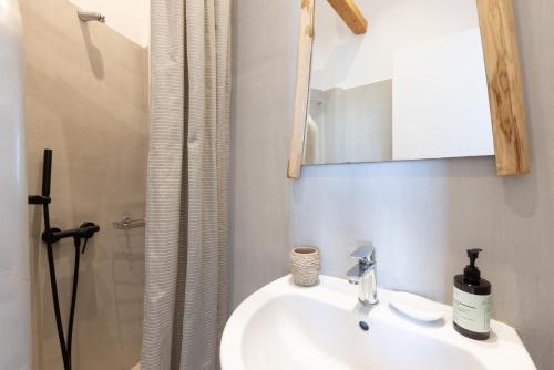 a bathroom with a sink and a mirror and a shower at Parosquare Central Suites in Parikia