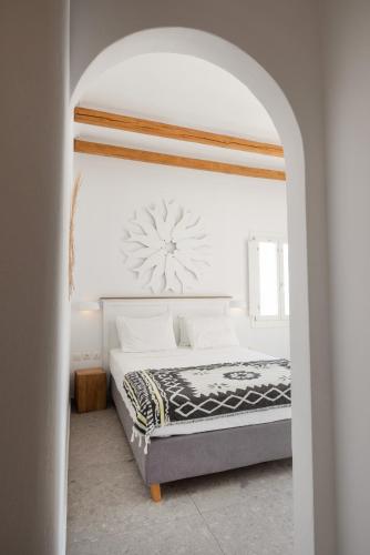 a white bedroom with a bed with a clock on the wall at Parosquare Central Suites in Parikia