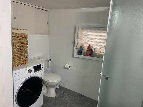 ein Badezimmer mit einem WC und einer Waschmaschine in der Unterkunft Good Place in Netanya