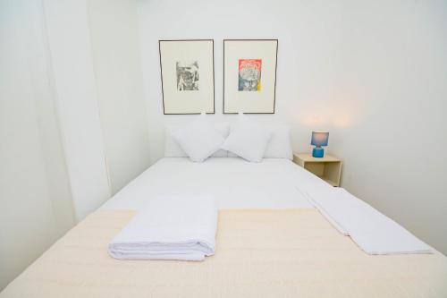 a bedroom with a white bed with two pictures on the wall at For You Rentals Cozy and charming 3-bedroom apartment in Madrid ASR18 in Madrid