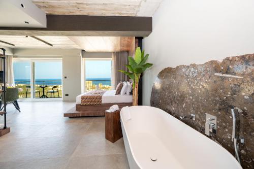 a bathroom with a bath tub and a bedroom at Salini Suites in Żebbuġ