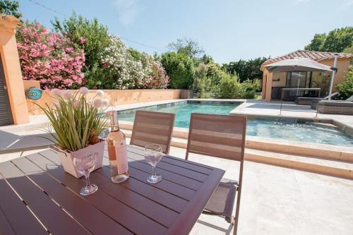 - une table en bois avec des verres à vin et une bouteille dans l'établissement Clos des Griottes, Clim Jacuzzi Parking, à Arles