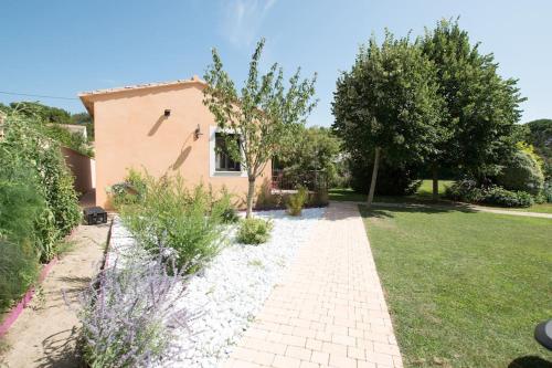 un jardin avec une maison et une passerelle dans l'établissement Clos des Griottes, Clim Jacuzzi Parking, à Arles