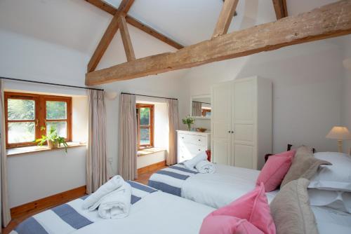a bedroom with two beds and two windows at Whitley Farm Dairy in Northleigh
