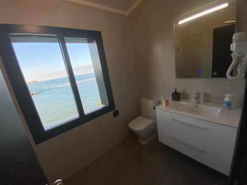 baño con lavabo y ventana con vistas al océano en Mundaka Beachfront House, en Mundaka