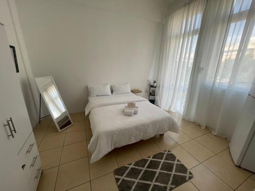 a white bedroom with a bed and a mirror at Godson Apartment in Haifa