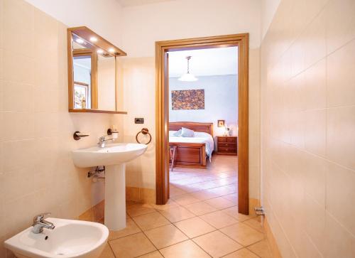 a bathroom with a sink and a mirror and a bedroom at Agriturismo Tenuta San Giuseppe in Cossano Belbo