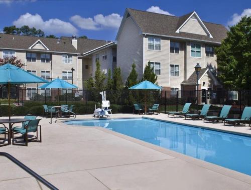 a swimming pool with chairs and umbrellas in front of a building at Sonesta ES Suites Birmingham Homewood in Birmingham