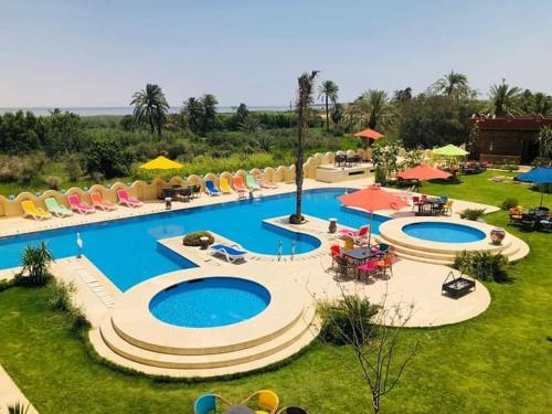 a large swimming pool with chairs and umbrellas at Tunis Pyramids Hotel - فندق اهرامات تونس in Tunis