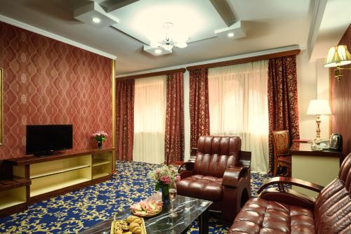 a living room with a couch chair and a television at Royal Plaza by Stellar Hotels, Yerevan in Yerevan