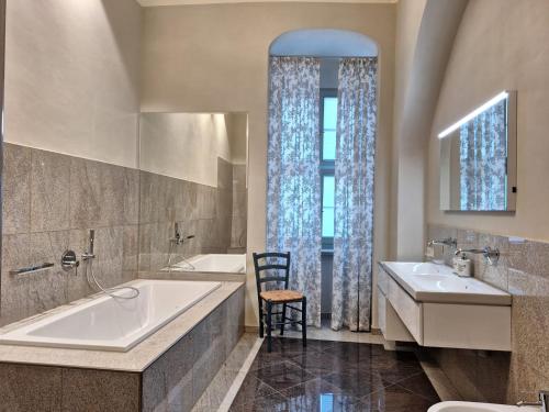 łazienka z 2 umywalkami, wanną i krzesłem w obiekcie Stadtpalais Marché-Suite maximal 2 Personen und 1 Kleinkind w mieście Budziszyn