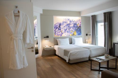 ニコシアにあるザ クラシック ホテルの白いベッドと壁に絵画が飾られたベッドルーム1室