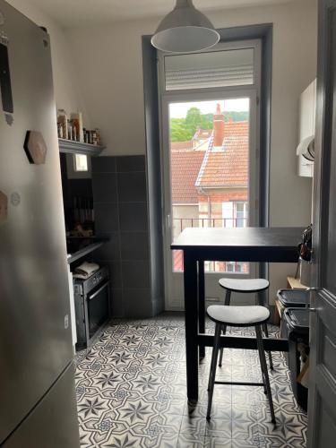 een keuken met een tafel en twee krukken en een raam bij Appartement Haussmannien in Épernay