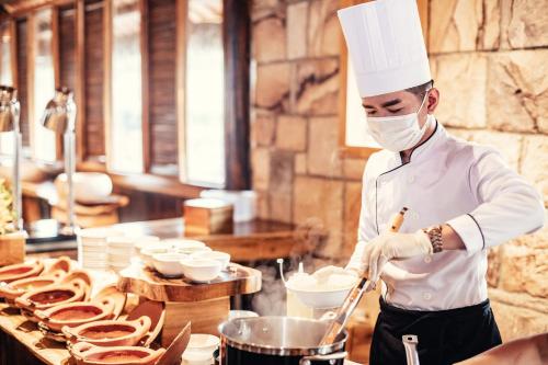 a chef wearing a mask preparing food in a kitchen at Ocean Bay Resort & Spa Phu Quoc in Phu Quoc
