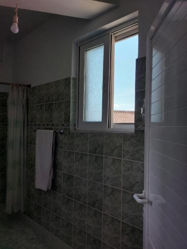 baño con ventana y ducha con cortina de ducha en Bebas apartment in the centre, en Sarandë
