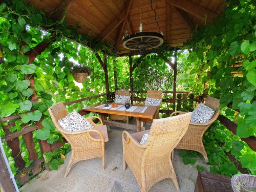 een patio met een houten tafel en stoelen en wijnranken bij Dália Apartmanok in Csopak
