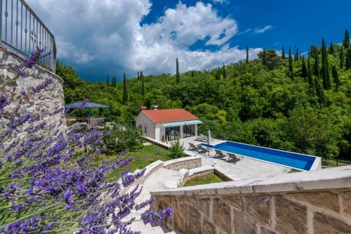 a house with a swimming pool and purple flowers at Villa Konavoski Miri in Gruda
