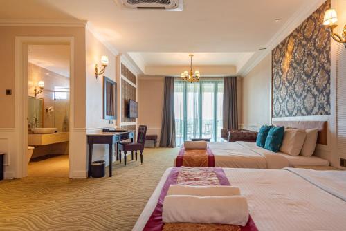 a hotel room with two beds and a desk at Tasik Villa International Resort in Port Dickson