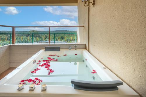 a hot tub with red flowers in a room with a window at Tasik Villa International Resort in Port Dickson