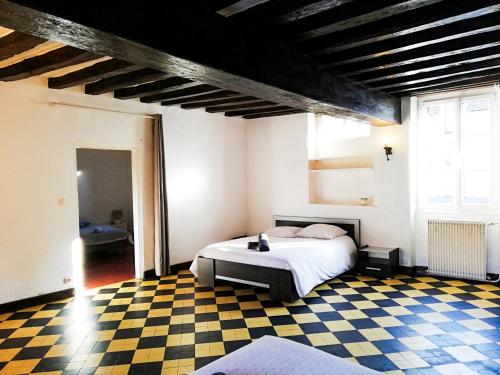 1 dormitorio con 1 cama y suelo a cuadros en L'ancien relai de poste de Magny-Cours, en Magny-Cours