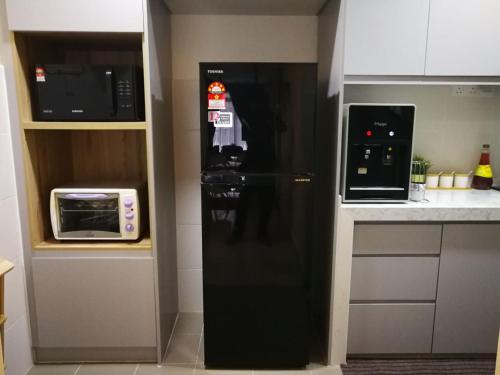 - un réfrigérateur noir dans une cuisine à côté d'un four micro-ondes dans l'établissement Bayu D'Awan Muslim Homestay Putrajaya, à Putrajaya