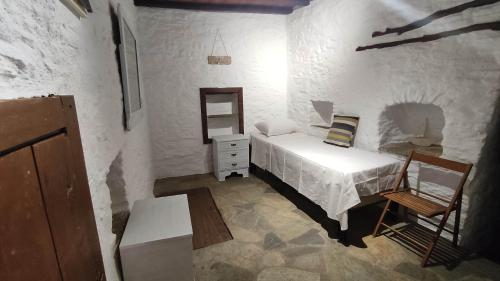 a small bedroom with a bed and a chair at Linardo low cost in Ano Syros