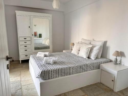 a white bedroom with a bed and a mirror at Sunny Stone Tinos House in Tinos