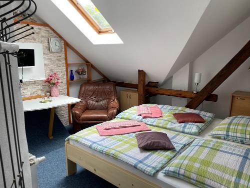 a bedroom with two beds and a table and a chair at Penzion Kamenný Dvůr in Vimperk