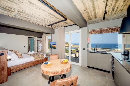 a bedroom with a bed and a table and a kitchen at Salini Suites in Żebbuġ