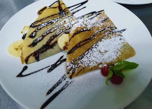 a white plate with a piece of cake with powdered sugar at Chvibiani Guesthouse & Bar in Ushguli