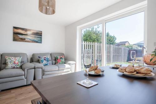 a living room with a table and a large window at Swn Y Mor - 4 Bedroom Holiday Home - Llanelli in Llanelli