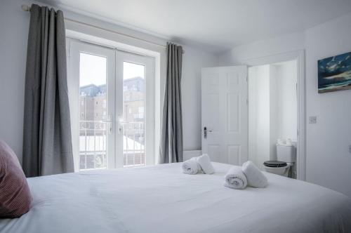 a bedroom with a large white bed with a window at Swn Y Mor - 4 Bedroom Holiday Home - Llanelli in Llanelli