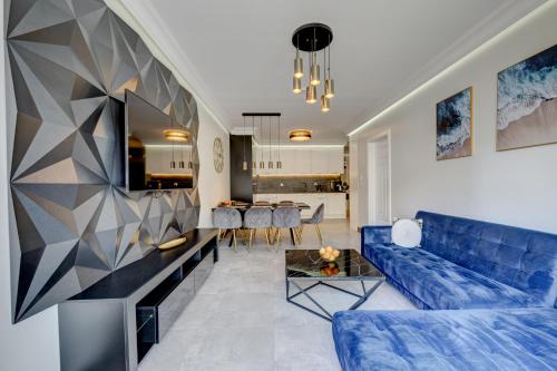a living room with a blue couch and a table at MALAGA APARTAMENTY BALTICUS in Międzyzdroje