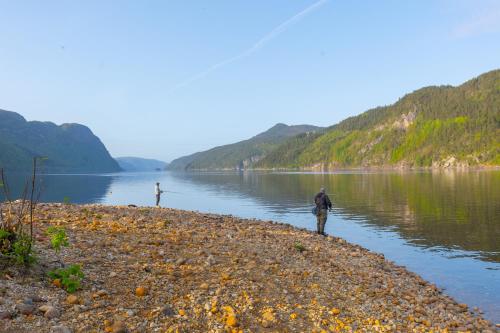 two people are standing on the shore of a lake at Sirdalsvatnet Hotel in Sirdal in Tonstad