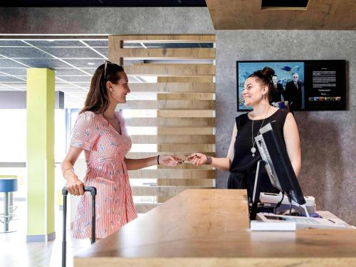 dos mujeres dándose la mano en una mesa en una oficina en Ibis Budget Perpignan Nord Rivesaltes, en Rivesaltes
