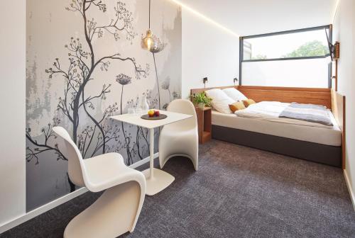 a bedroom with a bed and a table and chairs at TIN INN Montabaur l einfach gut - nachhaltig, innovativ, modern in Montabaur