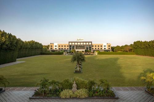 a large building with a large lawn in front of it at Radisson Hotel Kandla in Gandhidham